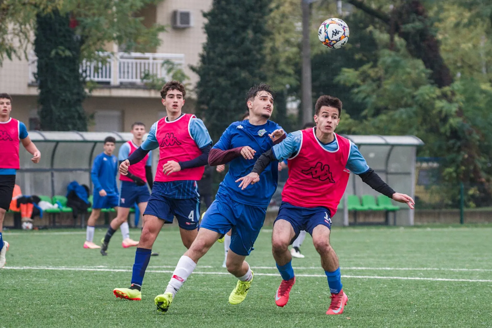 Tri nogometaša natječu se tko će udariti loptu glavom tijekom utakmice na zelenom terenu.